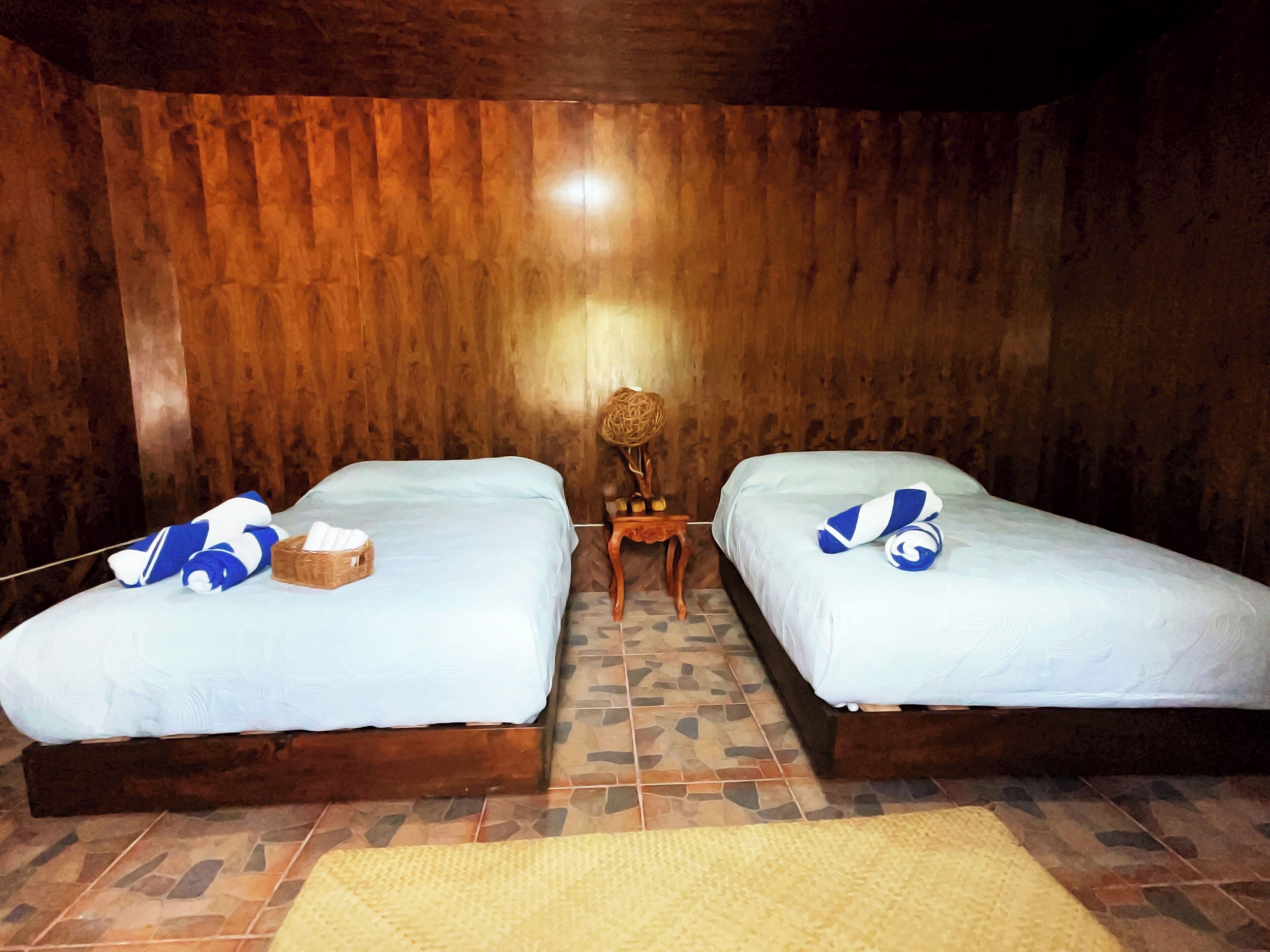 A room with two beds, a small wooden table, and a woven basket on one bed.