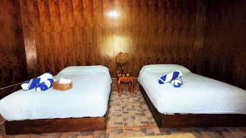 A room with two beds, a small wooden table, and a woven basket on one bed.
