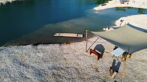 Una playa con una piscina cristalina, un banco de madera y una tienda de campaña.