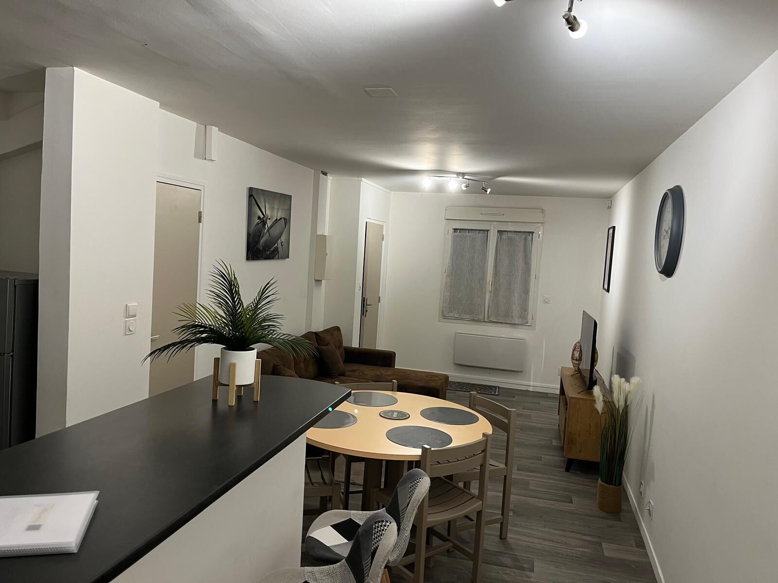 A compact living space with a kitchenette, a dining area with a round table, and a living room with a sofa.