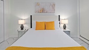Een keurig opgemaakt slaapkamer met een groot bed, twee nachtkastjes met lampen en een schilderij aan de muur.