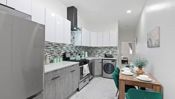 Een moderne keuken met grijze kastjes, een betegelde achterwand, een ingebouwde oven en een wasmachine.
