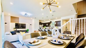 Ein modernes Wohnzimmer mit Essbereich, Küche und Treppe.
