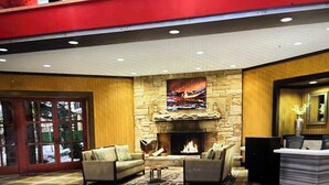 A lobby with a stone fireplace, two sofas, a coffee table, and a reception desk.