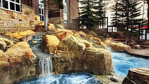 A rock garden with a waterfall, surrounded by stone walls and trees.