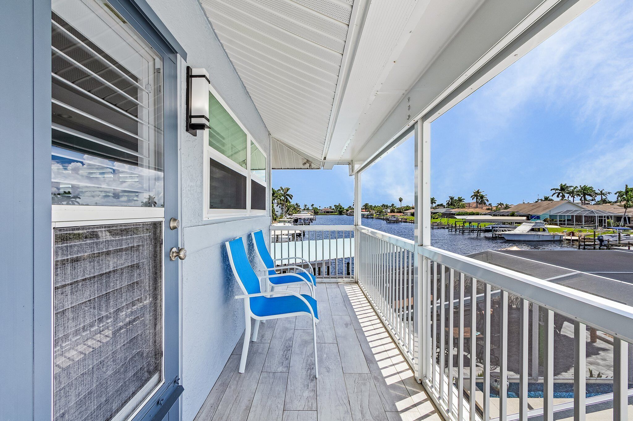 A balcony with a view of a marina, a pool, and palm trees.