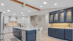 A modern kitchen with a central island, white cabinetry, and a marble backsplash. - 19th Place Paradise Awaits! (Cape Coral)