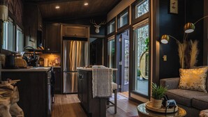 Een moderne keuken met donkere houten kasten, roestvrijstalen apparatuur en een groot eiland. Er is een gezellige zithoek met een bank en een bijzettafeltje.