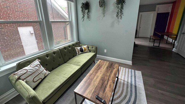 A living room with a green sofa, a wooden coffee table, and hanging plants.