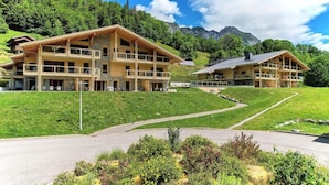 En toetages chalet med balkoner, beliggende i et bjergområde under en klar himmel.
