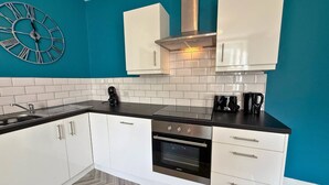 A modern kitchen with white cabinets, a black countertop, and a stainless steel oven.