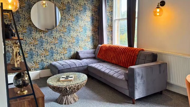 A modern living room with a sectional sofa, a round glass coffee table, and a decorative globe on a wooden stand.