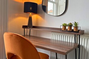 A modern room with a wooden desk, a chair, a lamp, and three potted plants on a shelf. - Smart 3-Bed in Hexham-Ideal for Workers & Families (Hexham)