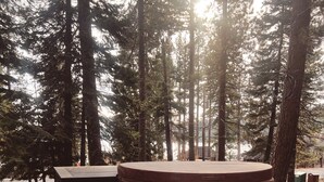 A wooden hot tub surrounded by rocks and pine trees. - Cozy lake-view cabin in Carnelian Bay (Carnelian Bay)