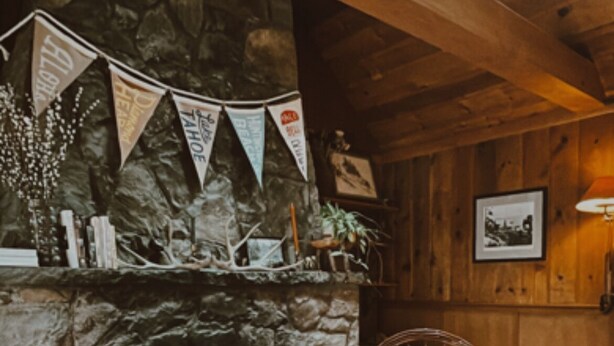 A cozy room with a stone fireplace, wooden beams, and a rustic chair. - Cozy lake-view cabin in Carnelian Bay (Carnelian Bay)