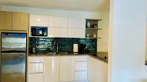 A modern kitchen with white cabinets, a stainless steel refrigerator, a microwave, and a sink. - Your getaway space walking distance to the beach (Luquillo Luquillo)