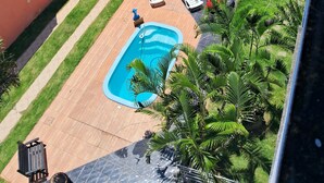 Un espace piscine aménagé sur le toit, avec un toit recouvert de tuiles, une piscine, des chaises longues et de la verdure environnante.