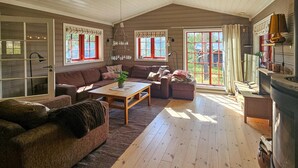 A cozy living room with a wooden floor, a brown sofa, a coffee table, and a fireplace. - Gorgeous home in Eggedal with sauna (Eggedal)