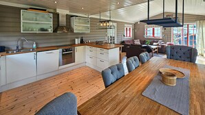 A modern kitchen with white cabinets, a wooden countertop, and a built-in oven. There is a dining area with a wooden table and blue upholstered chairs. - Gorgeous home in Eggedal with sauna (Eggedal)