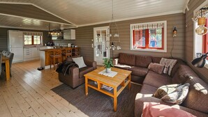 A spacious living room with a wooden coffee table, a brown sofa, and a kitchen area with a white refrigerator and wooden cabinets. - Gorgeous home in Eggedal with sauna (Eggedal)