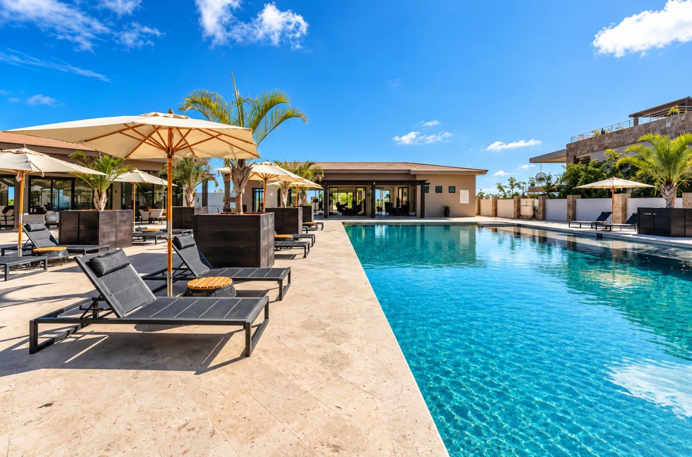 A poolside area with lounge chairs and umbrellas, a clear blue pool, and a modern building in the background.