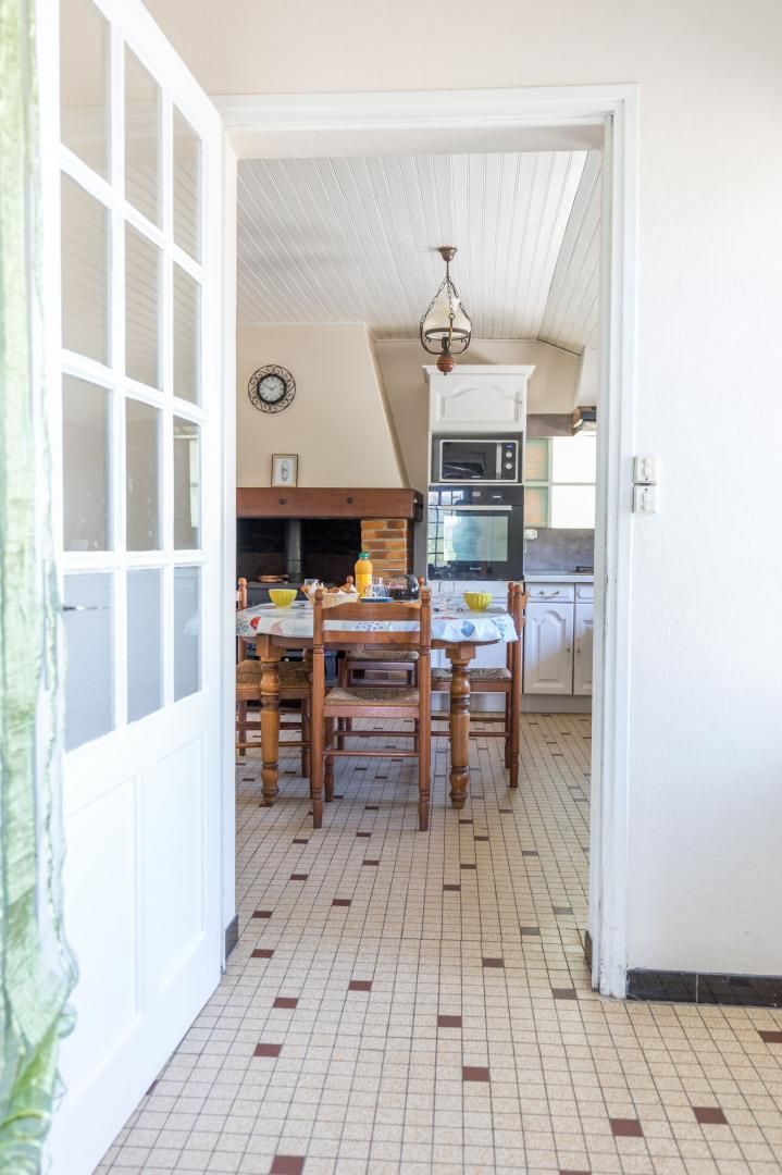 A kitchen with a tiled floor, wooden chairs, a table, and a hanging light fixture.