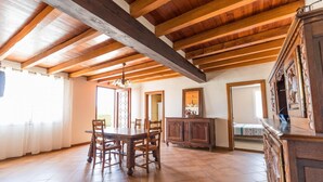 Une pièce spacieuse avec un plafond en bois, une table à manger avec des chaises, un buffet et un grand miroir.