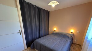 Een slaapkamer met een bed, twee bedlampen, een deur en een gordijn.