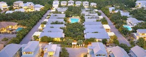 Uma área residencial com várias casas, uma rua central e uma piscina.