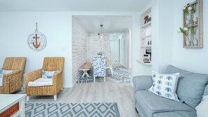 Ein modernes Wohnzimmer mit Korbstühlen, einem grauen Sofa und einem Essbereich mit Tisch und Stühlen.