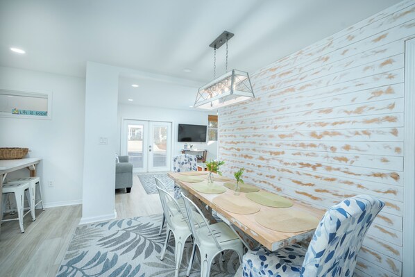A modern dining area with a wooden table, white chairs, and a patterned rug.