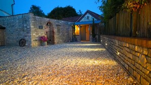 A stone building with a gravel driveway leading to a wooden door.