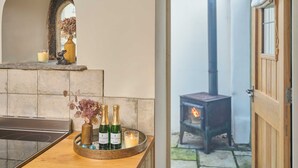 A kitchen area with a stone backsplash, a wooden counter, a mirror, and a view of a fireplace outside.