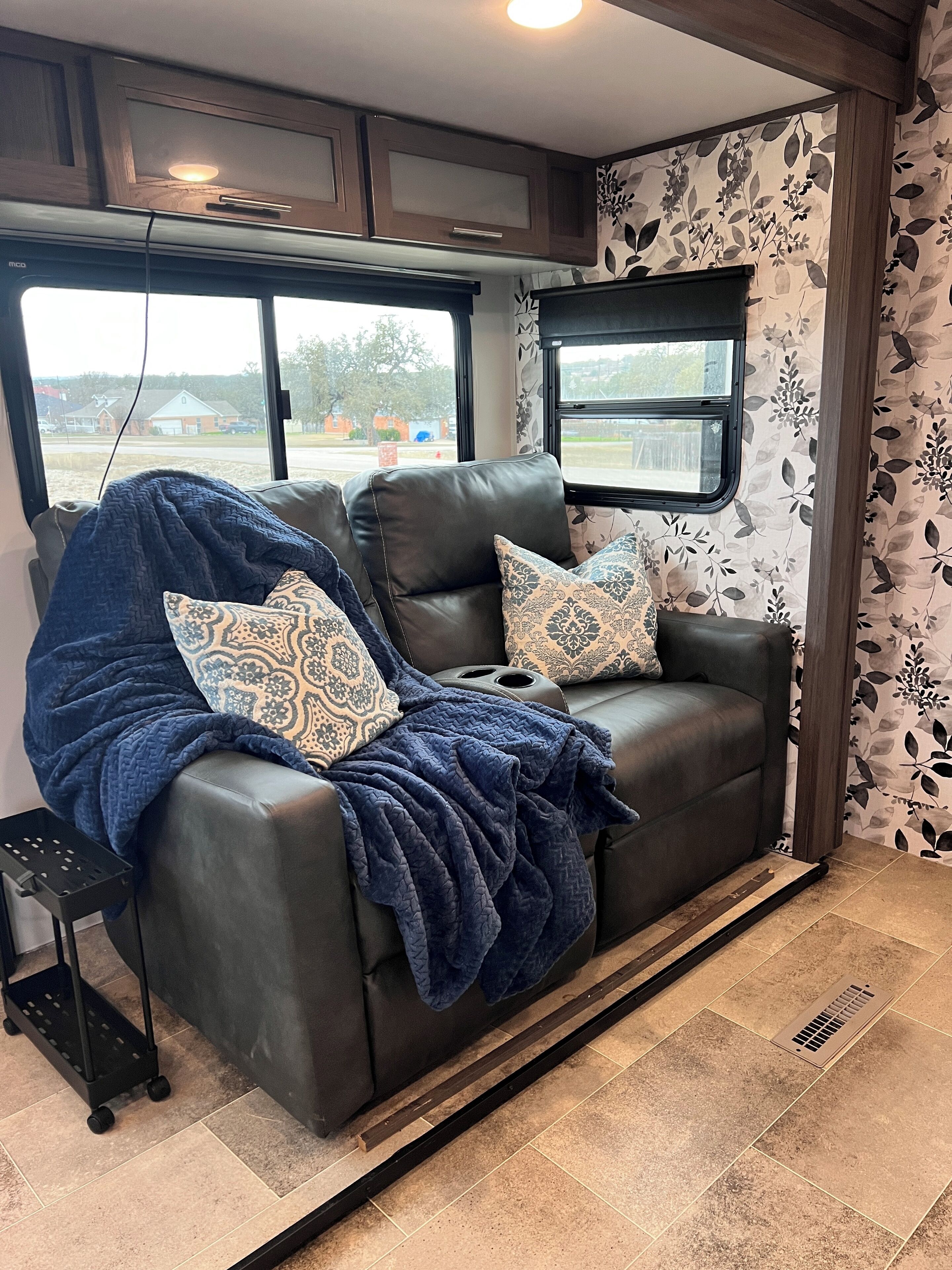 A cozy living area with a leather sofa, patterned cushions, and a blue blanket.