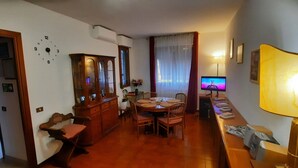 Un comedor con una mesa y sillas de madera, un armario y un televisor sobre un mueble.