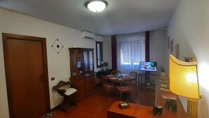 Una sala de estar con un aparador de madera, una mesa de comedor con sillas, un televisor y una lámpara.