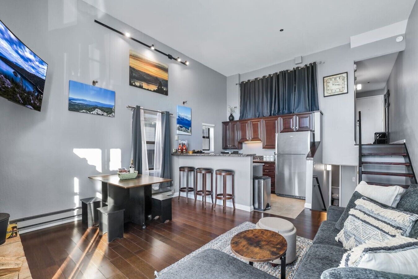 A modern kitchen with a central island, bar stools, and a refrigerator.