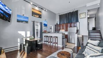 A modern kitchen with a central island, bar stools, and a refrigerator.