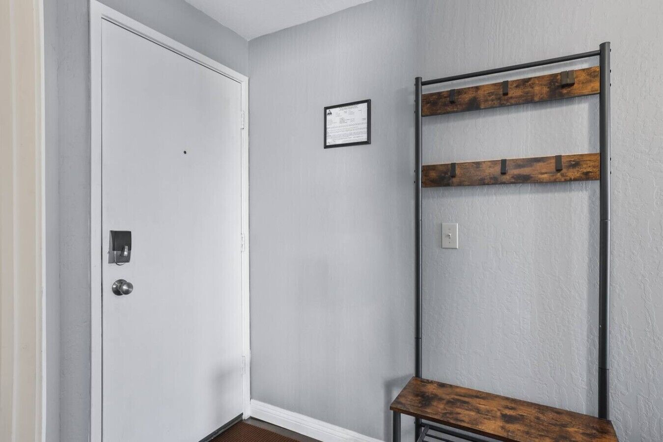 A room with a white door, a wall-mounted rack with wooden planks, and a small table with a wooden top.