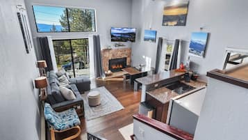 A modern living room with a fireplace, a dining area, and a kitchen with a stone countertop.