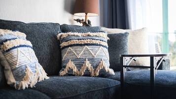Un canapé bleu foncé agrémenté de trois coussins décoratifs, une petite table et une lampe, le tout dans une pièce offrant une vue agréable.