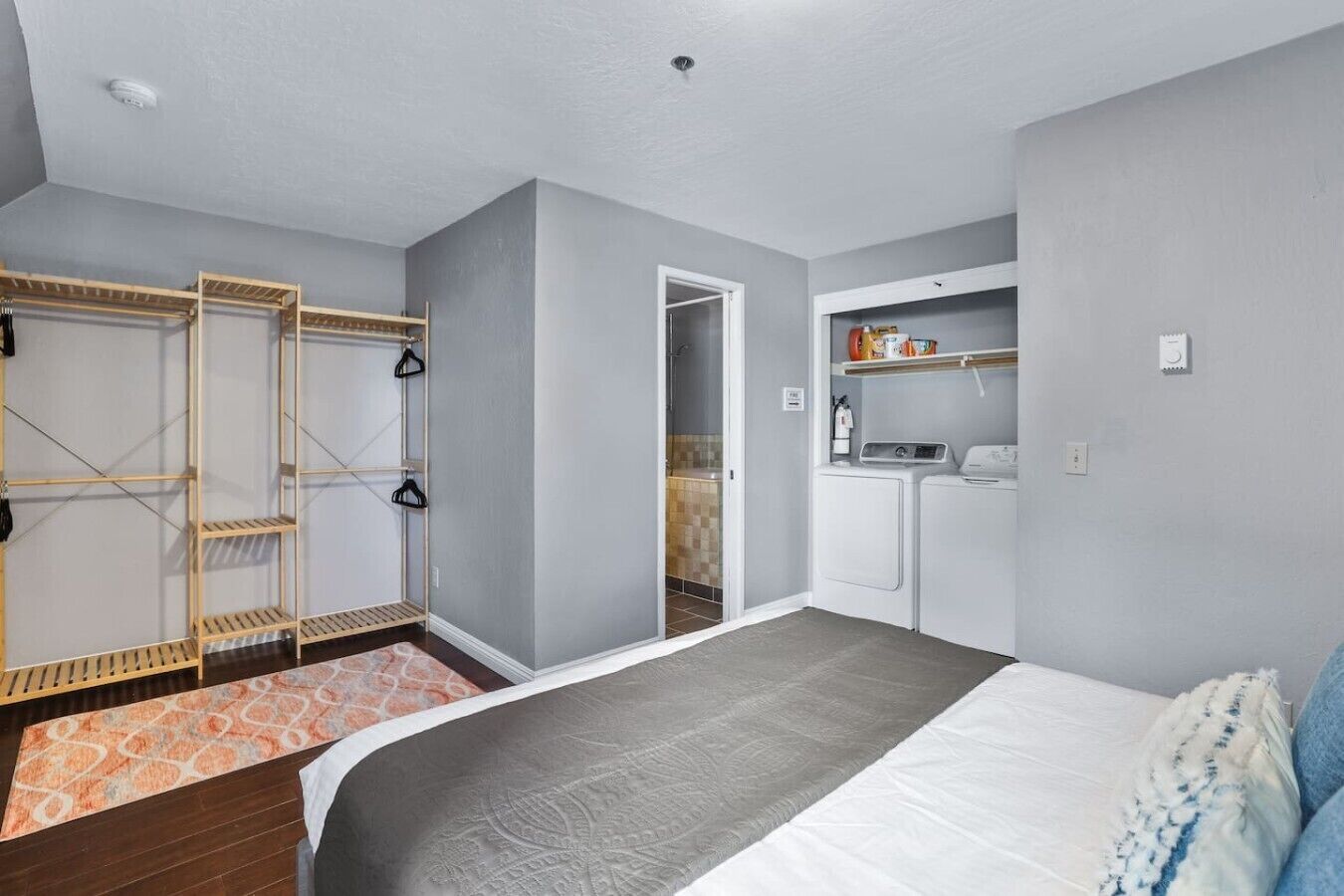 Une chambre à coucher comprenant un lit, une armoire, un coin buanderie et une salle de bain.