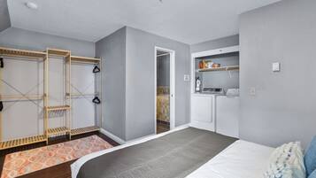 Une chambre à coucher comprenant un lit, une armoire, un coin buanderie et une salle de bain.