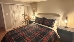 A bedroom with a plaid bedspread, a bedside table with a lamp, and a wardrobe. - 5BR Family home Near O’Hare, Easy Airport & Downtown Access, Garage Parking.  (Chicago)