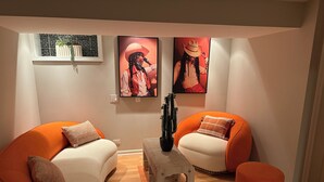 A living room with two orange armchairs, a white sofa, a small wooden side table, and a cactus plant. - 5BR Family home Near O’Hare, Easy Airport & Downtown Access, Garage Parking.  (Chicago)