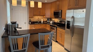 A modern kitchen with wooden cabinets, stainless steel appliances, a marble countertop, and pendant lighting. - 5BR Family home Near O’Hare, Easy Airport & Downtown Access, Garage Parking.  (Chicago)
