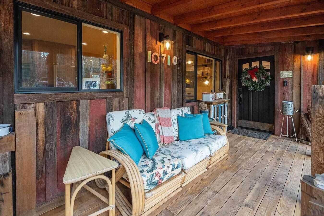 Un interior de madera con un sofá y una pequeña mesa, una puerta con un número, y una corona navideña.