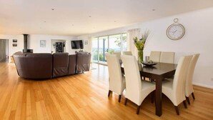 A spacious living area with a sofa set, a dining table with chairs, and a large window offering a view. - Bruny Horizon - Where the Country meets the Sea (North Bruny)