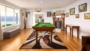 A spacious room with a pool table, a fireplace, and a view of the outdoors through large windows. - Bruny Horizon - Where the Country meets the Sea (North Bruny)