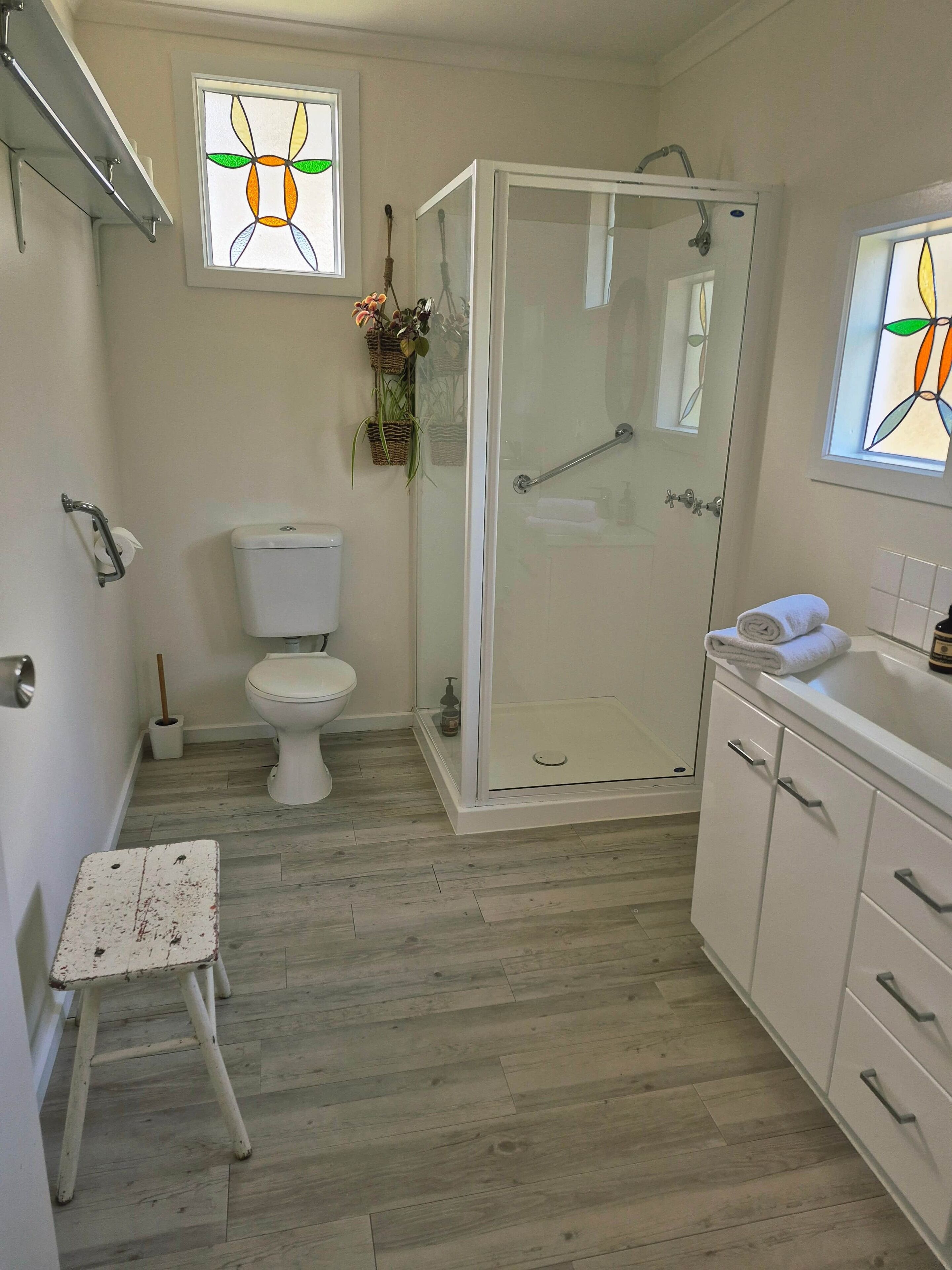 A modern bathroom with a glass shower enclosure, a toilet, and a sink with a towel on the counter.
